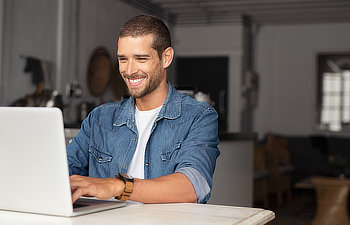 happy young businessman using laptop at home