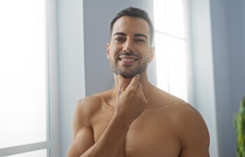 Handsome young hispanic man in a spa salon interior smiling and touching his beard